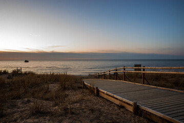 Obraz premium wooden path to the beautiful sunset beach