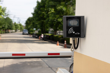A red and white traffic barrier with a camera on top of it. A yellow and red traffic barrier with a sign. automatic entry system
