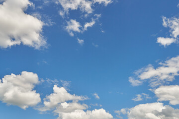 White fluffy clouds in the sky. Blue sky and cloud cover on a sunny summer day. Empty background, copy space
