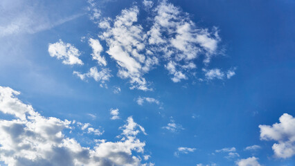 White fluffy clouds in the sky. Blue sky and cloud cover on a sunny summer day. Empty background, copy space