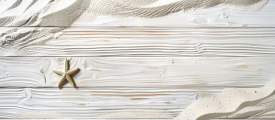 Sand on a white wooden surface with a summer theme. Overhead view with space for text.
