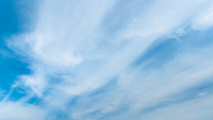 White fluffy clouds in the sky. Blue sky and cloud cover on a sunny summer day. Empty background, copy space