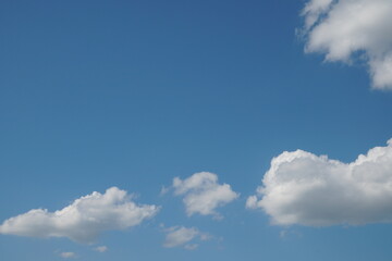 White fluffy clouds in the sky. Blue sky and cloud cover on a sunny summer day. Empty background, copy space
