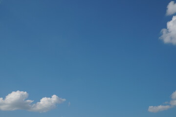 White fluffy clouds in the sky. Blue sky and cloud cover on a sunny summer day. Empty background, copy space