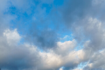 White fluffy clouds in the sky. Blue sky and cloud cover on a sunny summer day. Empty background, copy space