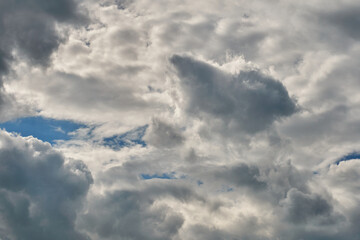 White fluffy clouds in the sky. Blue sky and cloud cover on a sunny summer day. Empty background, copy space