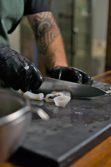Chef Expertly Slicing Fresh Squid on Cutting Board in Commercial Kitchen