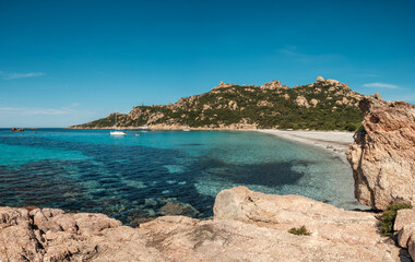 Obraz premium Yachts in the bay at Roccapina beach on the south west coast of Corsica overlooked by the Genoese Tour de Roccapina and Lion of Roccapina, a rocky outcrop in the shape of a lion
