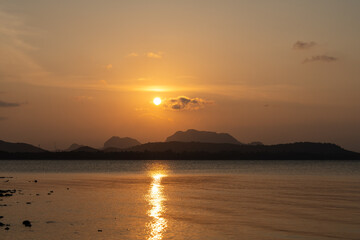 The sunset over the calm sea with reflections reflecting the beauty of nature. In the atmosphere of brown and yellow light, it is very beautiful.