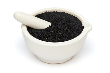 Close-up of Dry Organic Black Cumin (Nigella sativa) or kalonji, in white ceramic mortar and pestle, isolated on a white background.