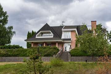 Beautiful old brick pink house.Two-story house with beautiful balcony. Stones big staircase. The green plant wall. Garden landscape design. 