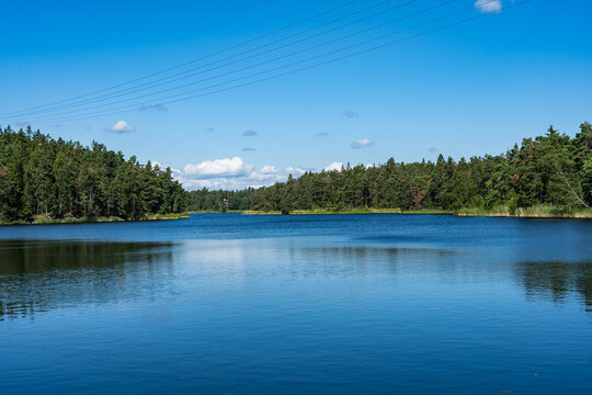 Beautiful panoramic view of the lake or the bay of the Baltic Sea. The rocky shores are covered with forests pines, spruces, firs, coniferous trees. Reflections in water in sunny day in Scandinavia.