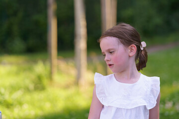 A cute girl, missing one tooth, playing joyfully in the summer heat at the playground.