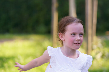 Preschool girl with a gap in her smile, enjoying a sunny day on the playground.