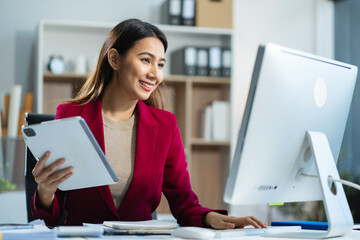 Business women hand working with tablet and laptop computer with documents on office desk in modern office.