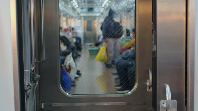 A blurred view of the inside of a running commuterline train car in the morning with passengers sitting and standing inside
