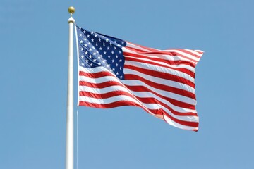 Obraz premium A large American flag waving in the wind against a clear blue sky