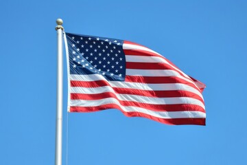 A large American flag waving in the wind against a clear blue sky