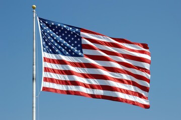 A large American flag waving in the wind against a clear blue sky