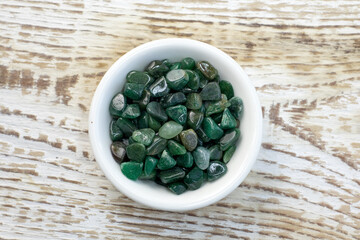 Macroshooting of natural mineral rock specimen - tumbled green aventurine gemstone on beige background