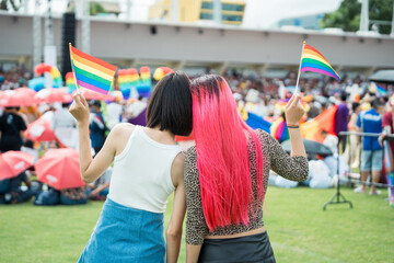 Fototapeta premium Celebrate in pride month festival. Pride movement transgender asian couple lesbian LGBT holding rainbow flag for freedom. Gatherings of friends in parade communities celebrating LGBTQ+ causes.