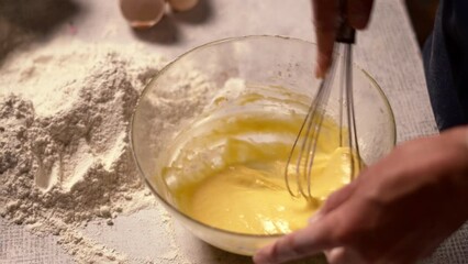 close up of chef's hands mixing eggs and flour in glass bowl, baker preparing dough for cakes or cookies