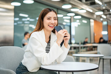 Young asian business woman with smartphone working in the office. Start up freelancer people posing while using mobile cell phone working in the modern office. Lifestyle business female.