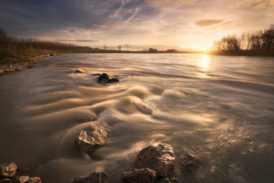 sunset on the Ebro river as it passes through Alfaro, La Rioja, with the water running between the rocks in the foreground