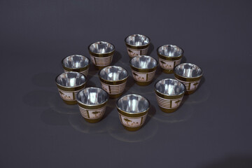 a set of gold oriental tea cups, on a gray background. Front view and high angle. © Sefianto Studios