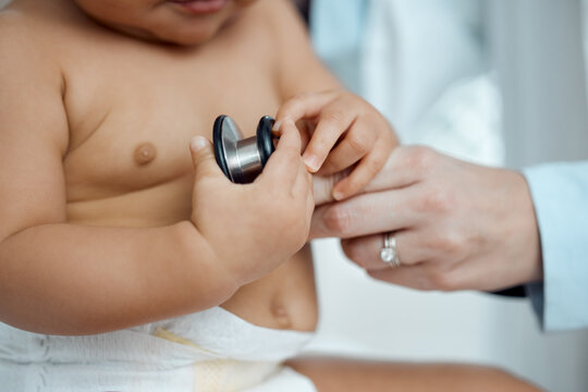 Stethoscope, hands of baby and doctor in clinic for check up, healthcare and progress for growth. Child, pediatrician and touching equipment for post natal assessment, development and cardiology