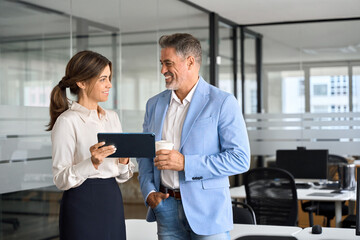 Happy professional smiling businessman and businesswoman having conversation at work. Executives...