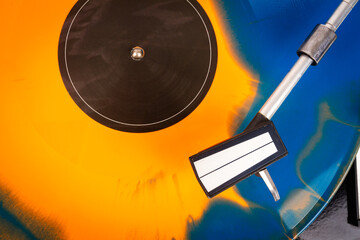 Close up of turntable needle on a vinyl record. Turntable playing vinyl. Needle on rotating orange...