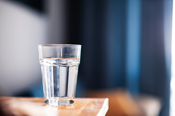 Captured in dark blue tones, a glass of water on a kitchen table evokes a sense of calm and relaxation