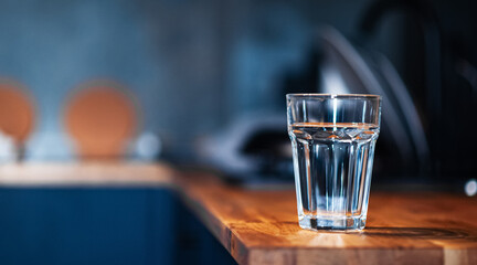 glass of water on the kitchen table in dark blue tones