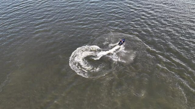 Jezioro mężczyznę pływa na skuterze wodnym, sporty wodne naz g&oacute;ry, zdjęcia z lotu ptaka, widok z drona, Mężczyznę pływa na skuterze wodnym robi piruety, wodny Sport, z g&oacute;ry, zdjęcia z lotu ptaka.