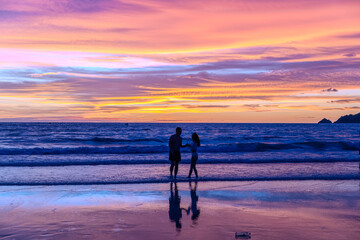 Silhouette of parasailing and people on the beach with the Most beautiful and colourful sunset on Patong Beach Phuket Island Thailand