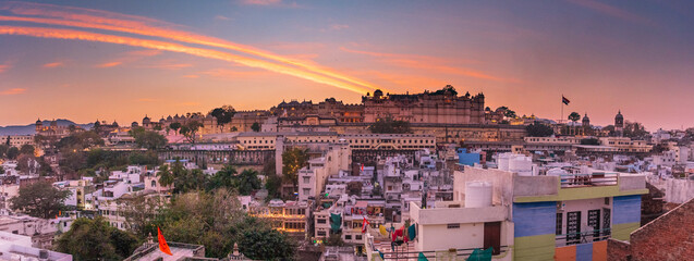 City palace illuminating the udaipur skyline at sunset. The city palace glowing at sunset in udaipur, india, with its massive structure towering over the city below. India, Rajasthan