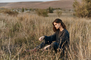 Young woman relaxing in tall grass field, engrossed in phone conversation