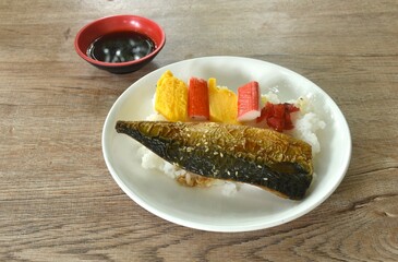 grilled saba fish or mackerel on rice topping sweet egg and crab stick couple pickled cabbage in plate dipping black sweet soybean sauce