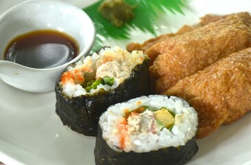 Inari Sushi Japanese food made from rice wrapped by fried tofu and maki rice stuffed sweet egg roll seaweed with wasabi dipping soy sauce on plate 