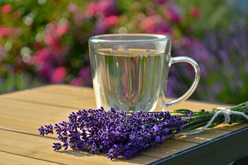 napój z lawendy w szkalnce na stoliku ogrodowym, lawenda na stole obok szklnki, lavender drink in glass and lavender flowers, drink with lavender and lavender flowers on bamboo coffee table  © kateej