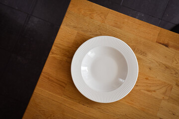Ceramic white flat plate for food on wooden table top view