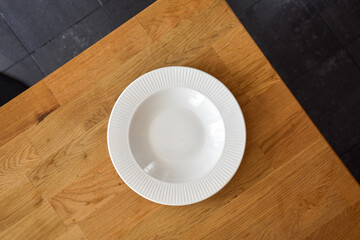 Ceramic white flat plate for food on wooden table top view