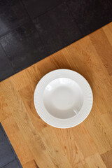 Ceramic white flat plate for food on wooden table top view
