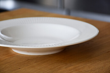 Ceramic white flat plate for food on wooden table top view