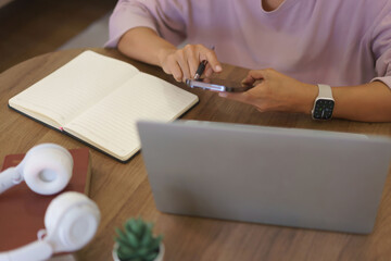 Obraz premium Female entrepreneur working to searching business data on smartphone and writing notes in paper