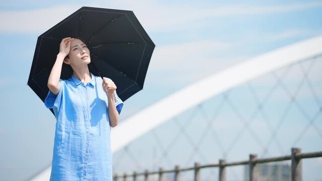 日傘をさして散歩する若い女性　ライフスタイルイメージ