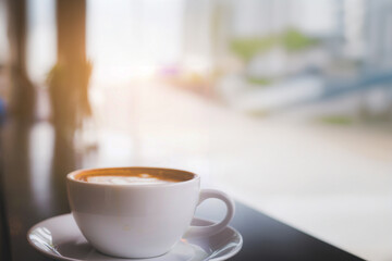 Cup of hot coffee on the table with coffee shop or cafe background in the morning