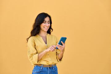 Young middle eastern brunette woman in casual clothes using mobile cellphone app for communication, shopping, buying, trading online. Smiling arabian girl holding smartphone phone, scrolling, typing