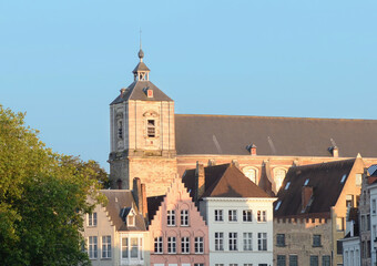Naklejka premium Side gable of the Saint Walburga church with some typical Flemish houses on a summer day with blue sky in Bruges, Flanders, Belgium
